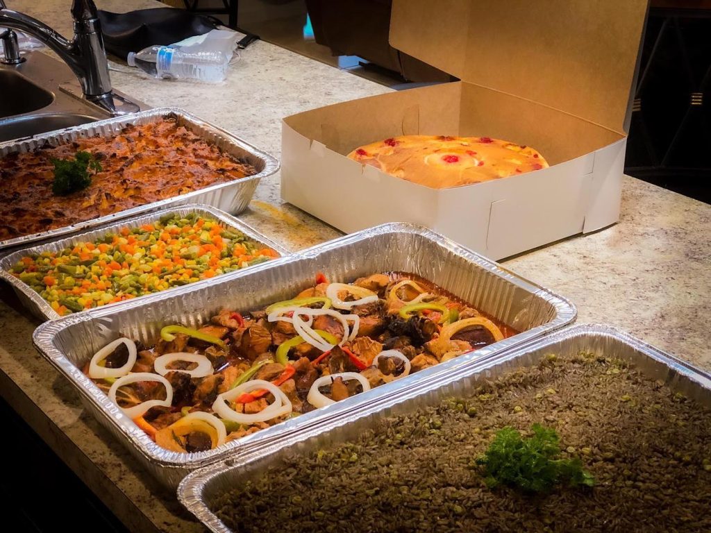 A selection of diverse dishes displayed in trays on a counter, showcasing an array of colors and textures.