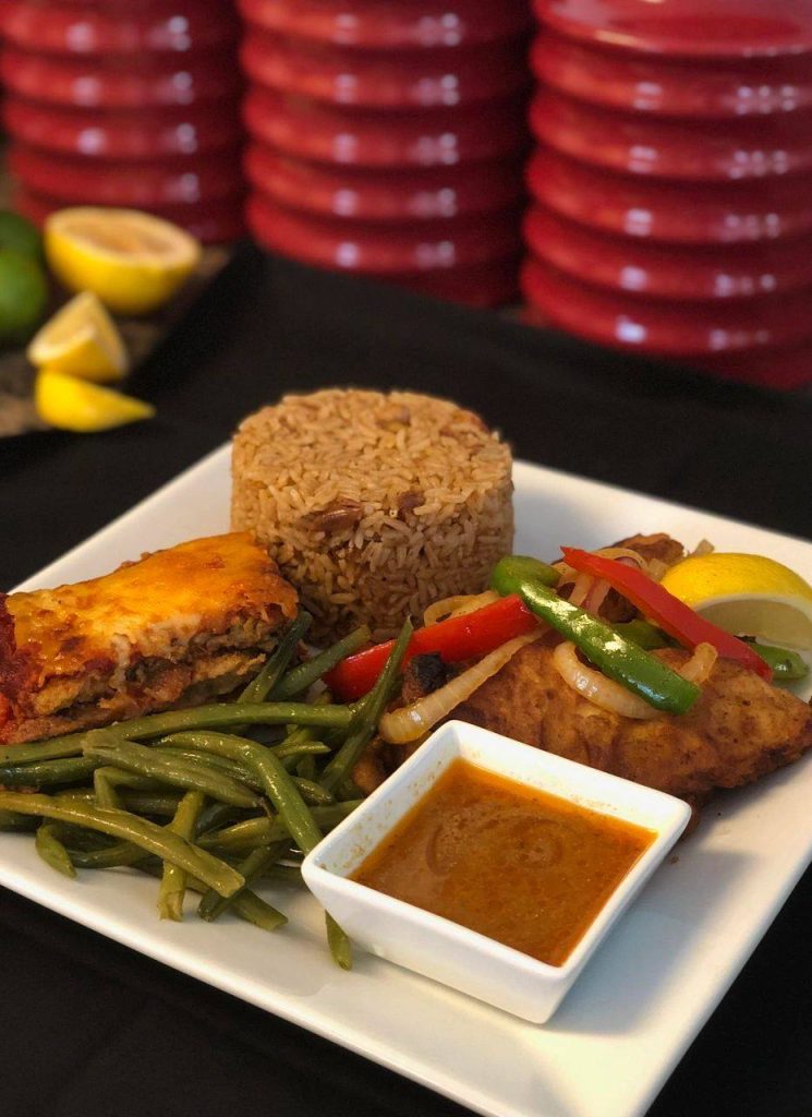 A plate featuring green beans, fluffy rice, and traditional Haitian cuisine, arranged appetizingly for a balanced meal.