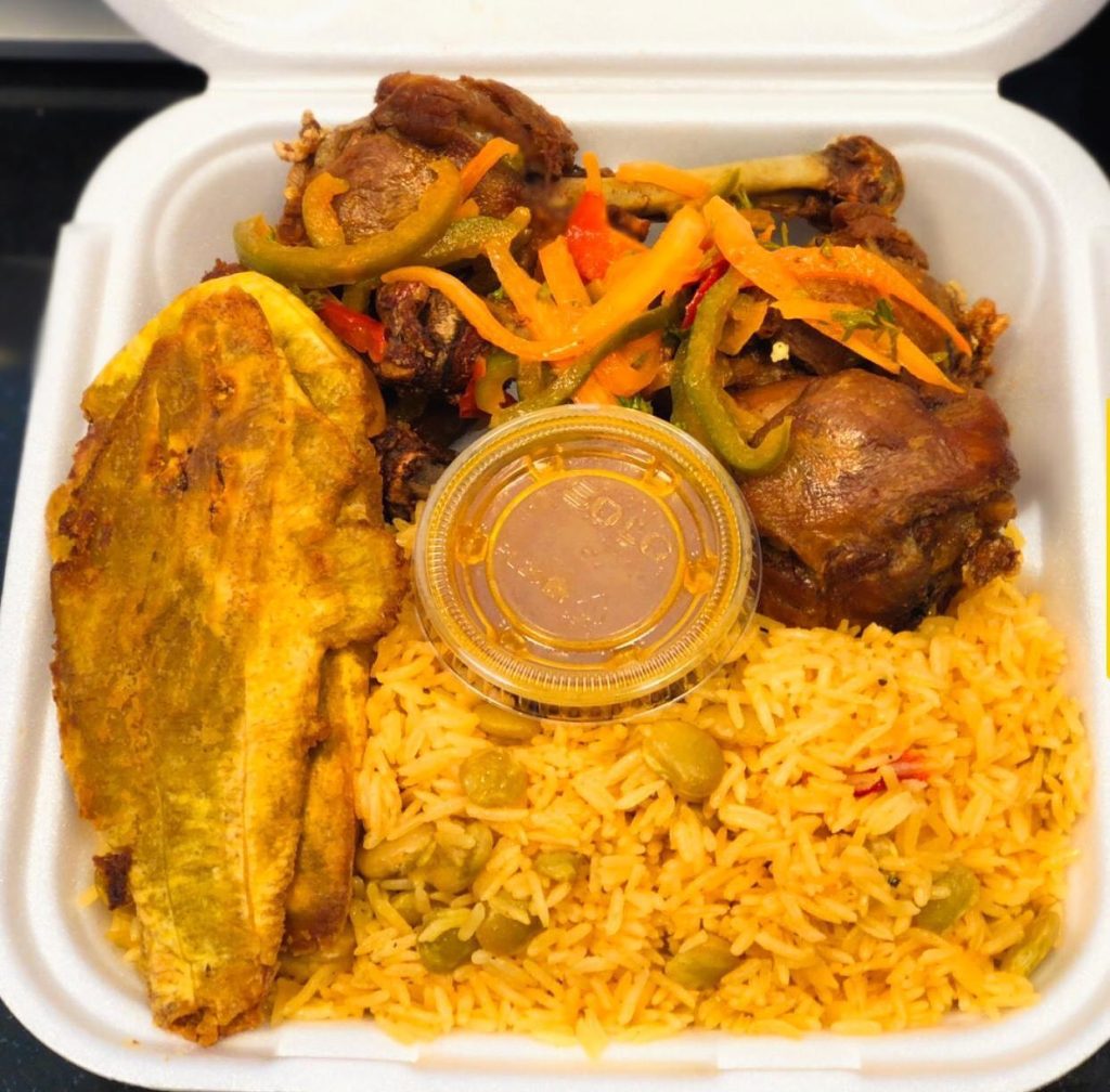Container filled with rice, Haitian pie, and colorful vegetables, ready for a delicious meal.