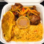 Container filled with rice, Haitian pie, and colorful vegetables, ready for a delicious meal.