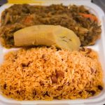 A tray of Haitian food featuring rice, plantains and vegetables, ready for a passenger's meal during the flight.