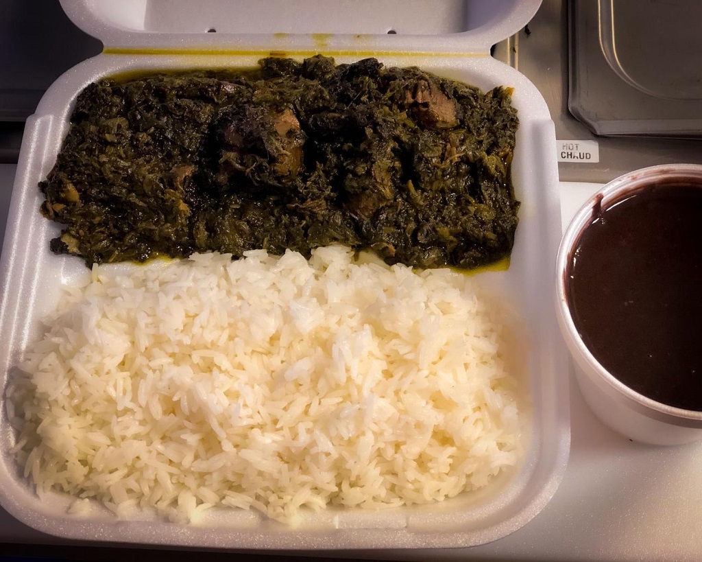 A tray authentic Haitian food with rice and greens