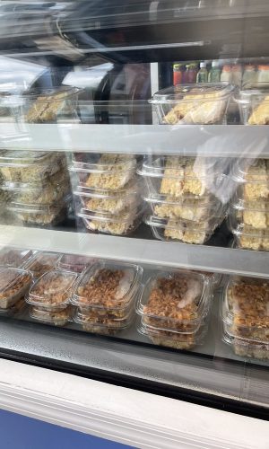 A display case showcasing a variety of food items in a store, highlighting fresh produce and prepared meals.