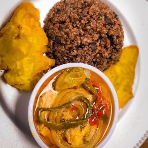 A white plate featuring a bowl filled with a colorful assortment of food.